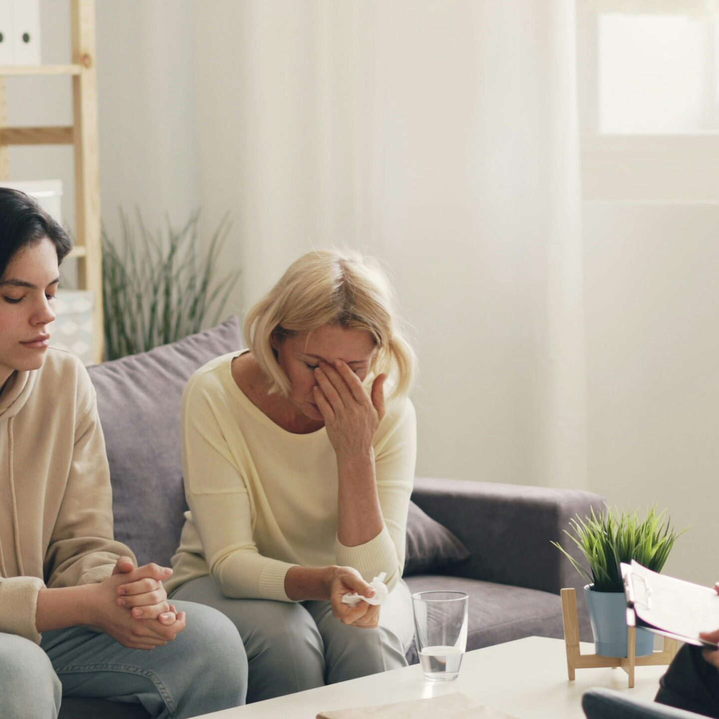 Three women sitting on a couch talking to each other